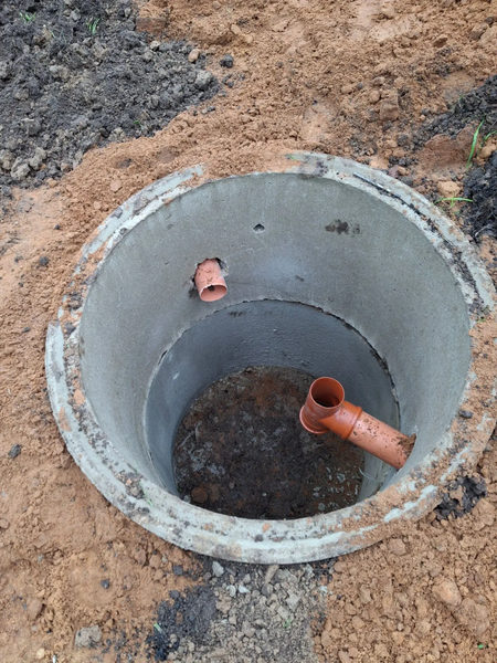 Камера септика из бетонного кольца с оранжевыми трубами